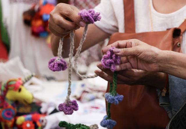 (260819) -- MEXICO CITY, Aug. 19, 2026 (Xinhua) -- Visitors look at crocheted ornaments during the 12th Indigenous Cultures Festival at Constitution Square in Mexico City, capital of Mexico, Aug. 18, 2026. Inside a large exhibition tent, visitors browse goods and taste local specialty drinks, while artisans demonstrate traditional skills such as embroidery. The festival will run until Aug. 23. (Xinhua/Liu Wenhui)
