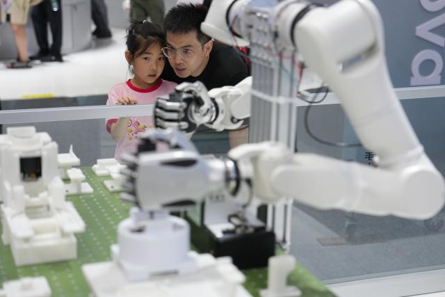 (260819) -- BEIJING, Aug. 19, 2026 (Xinhua) -- A man and a child watch the demonstration of a dexterous robotic hand during the 2026 World Robot Conference in Beijing, capital of China, Aug. 19, 2026. Themed "Human-Robot Symbiosis, Production-Demand Convergence," the 2026 edition of the conference kicked off here on Wednesday. (Xinhua/Ju Huanzong)