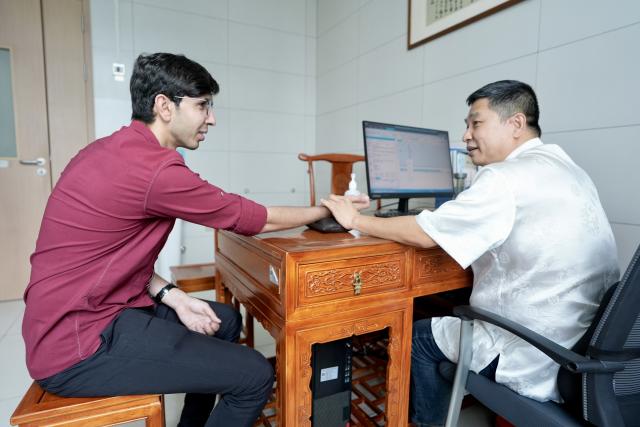 (260819) -- YINCHUAN, Aug. 19, 2026 (Xinhua) -- A doctor (R) feels the pulse of Mohammad Abdi at Ningxia Chinese Medicine Research Center in Yinchuan, northwest China's Ningxia Hui Autonomous Region, on Aug. 15, 2026. Mohammad Abdi, a 26-year-old Iranian student, came to China in 2023 to study clinical medicine at Ningxia Medical University.
   He was introduced to traditional Chinese medicine (TCM) at an early age. After seeing his uncle receive cupping therapy in Iran, he became curious about this traditional medical practice. Later, as a medical student in China, he had the opportunity to take professional TCM courses. On weekends, Abdi visits Ningxia Chinese Medicine Research Center to experience various TCM therapies.
   "I was a gym rat, so I initially thought TCM practices were too simple to be effective," he said. However, as he learned more about TCM, he was impressed by its depth and effectiveness. He recommended Baduanjin, a traditional Chinese breathing and stretching exercise, to his fellow international students, while he especially enjoys tuina massage combined with cupping therapy, which helps relieve the stress of his studies and clinical internship.
   For Abdi, TCM is more than a way to treat diseases; it is also a health philosophy that can be integrated into daily life. He believes ordinary people can benefit from TCM-based wellness practices, while professional doctors can use TCM techniques to treat patients.
   TCM is now expanding its global presence and joining the worldwide conversation on health and lifestyle. Inspired by growing interest in Chinese lifestyles overseas, Abdi hopes to continue exploring TCM and become a skilled doctor, helping more people in his hometown benefit from traditional Chinese medicine. (Xinhua/Yang Zhisen)