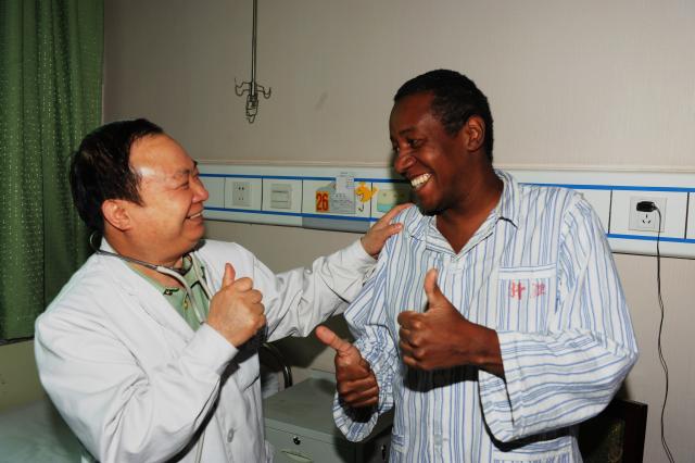 (260819) -- URUMQI, Aug. 19, 2026 (Xinhua) -- Zhuang Shihua talks with a Brazilian patient at the hospital affiliated to the Xinjiang Armed Police Corps in Urumqi, northwest China's Xinjiang Uygur Autonomous Region, May 4, 2011.
  Zhuang Shihua, a veteran hepatobiliary surgeon and former president of the hospital affiliated to the Xinjiang Armed Police Corps, has been in the country's far west for over five decades.
  His team has successfully completed more than 140,000 minimally invasive hepatobiliary surgeries, and made seven breakthroughs that filled the domestic gap in the field. Apart from clinical practice, Zhuang has cultivated a large number of key personnel, and supported grassroots medical workers who have stood firm on the front lines of public health.
  Zhuang's medical expertise brought him many opportunities to make a fortune, but he turned down the offers and stayed in Xinjiang.
  Zhuang often visited patients in the pastoral areas of Tianshan Mountains. He also provided financial assistance to over 70 underprivileged students and helped more than 690 households with patients out of poverty. (Photo by Ma Aiguo/Xinhua)