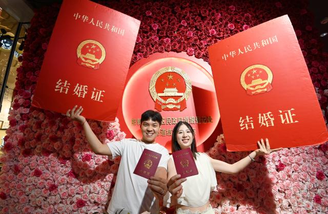 (260820) -- BEIJING, Aug. 20, 2026 (Xinhua) -- A couple pose for a photo after receiving their marriage certificates at a local marriage registering center in Handan, north China's Hebei Province, Aug. 19, 2026. Known as the Chinese version of the Valentine's Day, the Qixi Festival fell on Wednesday this year. (Photo by Hao Qunying/Xinhua)