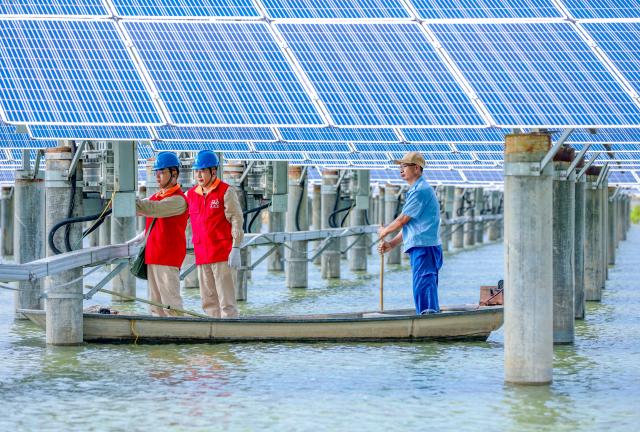 (260820) -- NANJING, Aug. 20, 2026 (Xinhua) -- Maintenance workers patrol a photovoltaic-aquaculture farm in Yangzhou, east China's Jiangsu Province, Aug. 19, 2026. The overall installed capacity of photovoltaic power-generating facilities in Jiangsu has exceeded 100-gigawatt mark to reach 100.08 gigawatts by the end of July 2026, according to the State Grid Jiangsu Electric Power Company. (Photo by Ren Fei/Xinhua)