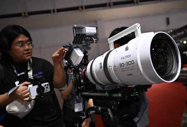 (260820) -- BEIJING, Aug. 20, 2026 (Xinhua) -- A visitor learns about a zoom lens for film-making during the 33rd Beijing International Radio, TV & Film Exhibition (BIRTV 2026) in Beijing, capital of China, Aug. 20, 2026. The ongoing 33rd Beijing International Radio, TV & Film Exhibition is held here from Aug. 19 to Aug. 22. (Xinhua/Zheng Huansong)