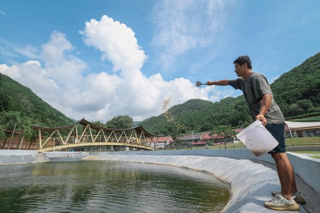 (260820) -- BAISHAN, Aug. 20, 2026 (Xinhua) -- A staff member feeds crabs at a cultivation base in Sandaogou Town of Baishan City, northeast China's Jilin Province, Aug. 19, 2026. Thanks to national highway G331 which opened for public transportation in September 2025, Sandaogou Town, once a remote mountainous town backward in development, has seized new opportunities to foster local businesses in cultivation, tourism and other services. (Xinhua/Xu Chang)