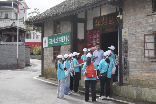 (260821) -- GUIYANG, Aug. 21, 2026 (Xinhua) -- Yan Jiayun, the first Party secretary stationed in Jieshang Village, briefs college students in front of the "Red Village Supermarket" in Jieshang Village of Gaopo Township, Guiyang, southwest China's Guizhou Province, July 11, 2026. TO GO WITH "Across China: Mountain village in SW China finds new path on Long March route" (Xinhua)