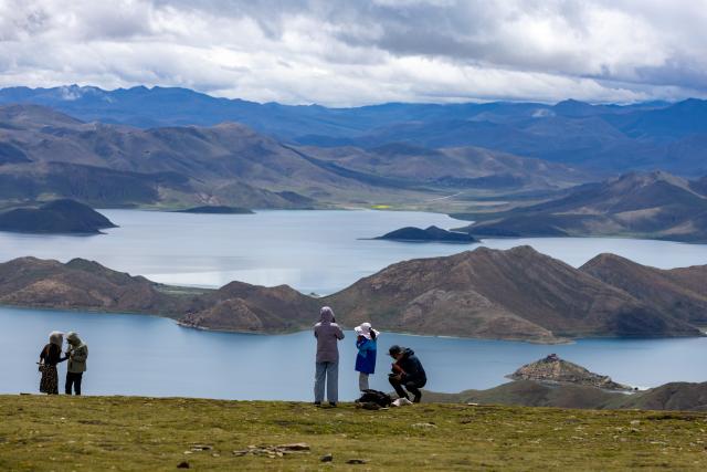 (260821) -- LHASA, Aug. 21, 2026 (Xinhua) -- Tourists visit Lake Yamzhog Yumco, Shannan City, southwest China's Xizang Autonomous Region, Aug. 20, 2026. (Xinhua/Jiang Fan)