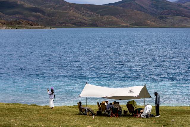 (260821) -- LHASA, Aug. 21, 2026 (Xinhua) -- Tourists visit Lake Yamzhog Yumco, Shannan City, southwest China's Xizang Autonomous Region, Aug. 20, 2026. (Xinhua/Jiang Fan)