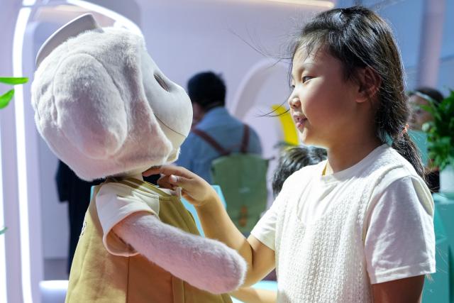 (260821) -- BEIJING, Aug. 21, 2026 (Xinhua) -- A child interacts with a companion robot during the 2026 World Robot Conference in Beijing, capital of China, Aug. 20, 2026. The conference, which runs from Wednesday through Sunday, has drawn more than 300 exhibitors from 26 countries, with over 3,000 products on display, including more than 300 debuts. (Xinhua/Ju Huanzong)