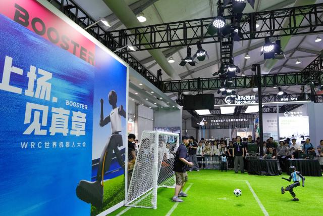 (260821) -- BEIJING, Aug. 21, 2026 (Xinhua) -- A humanoid robot plays football with a boy during the 2026 World Robot Conference in Beijing, capital of China, Aug. 20, 2026. The conference, which runs from Wednesday through Sunday, has drawn more than 300 exhibitors from 26 countries, with over 3,000 products on display, including more than 300 debuts. (Xinhua/Ju Huanzong)