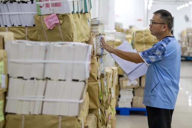 (260821) -- BEIJING, Aug. 21, 2026 (Xinhua) -- A staff member checks the textbooks for the upcoming new semester at a delivery center in Wuzhou, south China's Guangxi Zhuang Autonomous Region, on Aug. 21, 2026. Various departments across the country are getting ready for the upcoming new semester. (Photo by He Huawen/Xinhua)
