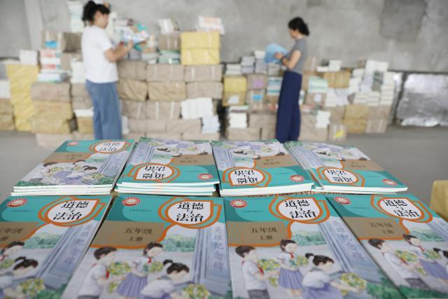 (260821) -- BEIJING, Aug. 21, 2026 (Xinhua) -- Staff members sort out textbooks for the upcoming new semester in Wenxian County of Jiaozuo, central China's Henan Province, on Aug. 20, 2026. Various departments across the country are getting ready for the upcoming new semester. (Photo by Xu Hongxing/Xinhua)