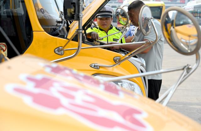 (260821) -- BEIJING, Aug. 21, 2026 (Xinhua) -- A traffic police officer inspects school buses in Cixian County of Handan, north China's Hebei Province, on Aug. 20, 2026. Various departments across the country are getting ready for the upcoming new semester. (Photo by Hao Qunying/Xinhua)