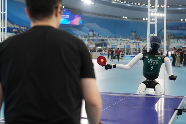 (260822) -- BEIJING, Aug. 22, 2026 (Xinhua) -- A humanoid robot plays table tennis with a man before the opening ceremony of the 2nd World Humanoid Robot Games in Beijing, capital of China, Aug. 22, 2026. (Xinhua/Ju Huanzong)