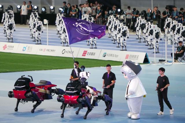 (260822) -- BEIJING, Aug. 22, 2026 (Xinhua) -- A humanoid robot waves the flag of the World Humanoid Robot Games during the opening ceremony of the 2nd World Humanoid Robot Games in Beijing, capital of China, Aug. 22, 2026. (Xinhua/Ju Huanzong)