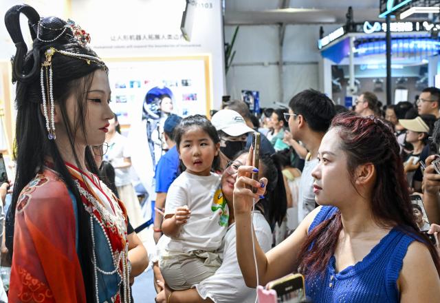 (260822) -- BEIJING, Aug. 22, 2026 (Xinhua) -- People view a humanoid robot at the 2026 World Robot Conference in Beijing, capital of China, Aug. 22, 2026. The conference, which runs from Wednesday through Sunday, has drawn more than 300 exhibitors from 26 countries, with over 3,000 products on display, including more than 300 debuts. Many people visited the conference on Saturday, the first open day of the event. (Xinhua/Chen Yehua)