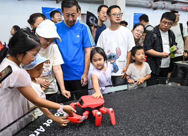 (260822) -- BEIJING, Aug. 22, 2026 (Xinhua) -- People view a crab-shaped robot at the 2026 World Robot Conference in Beijing, capital of China, Aug. 22, 2026. The conference, which runs from Wednesday through Sunday, has drawn more than 300 exhibitors from 26 countries, with over 3,000 products on display, including more than 300 debuts. Many people visited the conference on Saturday, the first open day of the event. (Xinhua/Chen Yehua)