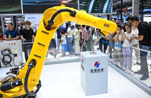 (260822) -- BEIJING, Aug. 22, 2026 (Xinhua) -- People view an industrial robot at the 2026 World Robot Conference in Beijing, capital of China, Aug. 22, 2026. The conference, which runs from Wednesday through Sunday, has drawn more than 300 exhibitors from 26 countries, with over 3,000 products on display, including more than 300 debuts. Many people visited the conference on Saturday, the first open day of the event. (Xinhua/Chen Yehua)