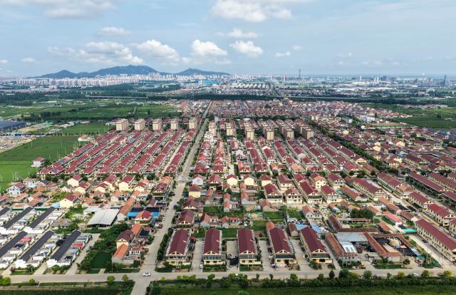 (260822) -- LIANYUNGANG, Aug. 22, 2026 (Xinhua) -- An aerial drone photo taken on Aug. 19, 2026 shows a view of the Xijidang Village, Zhewang Town of Lianyungang City, east China's Jiangsu Province. Zhong Baijun, Party secretary of Xijidang Village and head of the village committee, has spent 28 years serving his hometown in Zhewang Town of Lianyungang City, east China's Jiangsu Province.
  When he returned to the village to take up his post in 1998, the village collective had no industries and was in debt. Most residents made a living from farming, and many younger villagers left home to seek work elsewhere.
  Looking for new ways to develop the local economy, Zhong and other village officials traveled to other areas to explore potential industries. Leveraging the village's coastal location and the relatively abundant stock of discarded fishing nets, they gradually developed a nylon pellet processing industry.
  The industry initially grew through small workshops. To restructure the sector, the village invested 120 million yuan (about 17.9 million U.S. dollars) in building a standardized industrial park and later developed a model that allowed residents to benefit from the industry's growth through shareholding, local employment and dividends. By 2025, Xijidang's total industrial output reached 2.5 billion yuan (about 372 million U.S. dollars). The industry also created jobs for more than 1,600 local residents.
  As the collective economy grew, the village put more resources into improving community well-being. It organized cultural and sports activities, as well as model-family award campaigns, giving residents more opportunities to take part in community events.
  Over the past 28 years, Zhong has witnessed the village's industries expand, employment opportunities increase and collective income rise. "We should put the people's concerns first," Zhong said. (Xinhua/Ji Chunpeng)