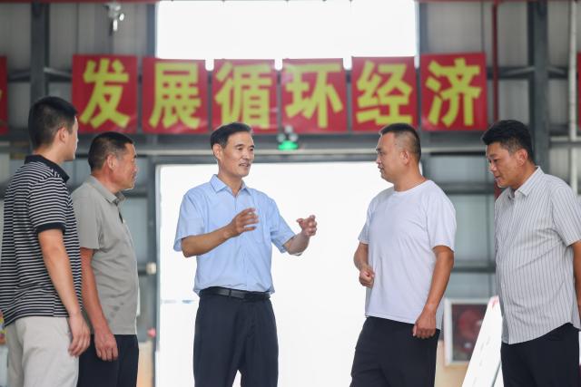 (260822) -- LIANYUNGANG, Aug. 22, 2026 (Xinhua) -- Zhong Baijun (C) discusses the company's development with village officials and employees at a village collective company in Xijidang Village, Zhewang Town of Lianyungang City, east China's Jiangsu Province, Aug. 19, 2026. Zhong Baijun, Party secretary of Xijidang Village and head of the village committee, has spent 28 years serving his hometown in Zhewang Town of Lianyungang City, east China's Jiangsu Province.
  When he returned to the village to take up his post in 1998, the village collective had no industries and was in debt. Most residents made a living from farming, and many younger villagers left home to seek work elsewhere.
  Looking for new ways to develop the local economy, Zhong and other village officials traveled to other areas to explore potential industries. Leveraging the village's coastal location and the relatively abundant stock of discarded fishing nets, they gradually developed a nylon pellet processing industry.
  The industry initially grew through small workshops. To restructure the sector, the village invested 120 million yuan (about 17.9 million U.S. dollars) in building a standardized industrial park and later developed a model that allowed residents to benefit from the industry's growth through shareholding, local employment and dividends. By 2025, Xijidang's total industrial output reached 2.5 billion yuan (about 372 million U.S. dollars). The industry also created jobs for more than 1,600 local residents.
  As the collective economy grew, the village put more resources into improving community well-being. It organized cultural and sports activities, as well as model-family award campaigns, giving residents more opportunities to take part in community events.
  Over the past 28 years, Zhong has witnessed the village's industries expand, employment opportunities increase and collective income rise. "We should put the people's concerns first," Zhong said. (Photo by Si Wei/Xinhua)