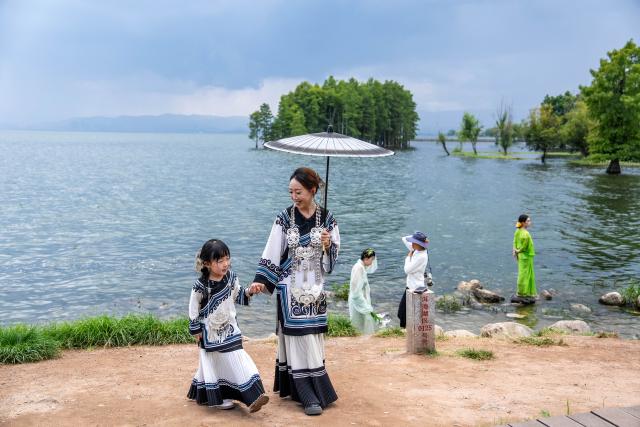 (260823) -- BEIJING, Aug. 23, 2026 (Xinhua) -- People visit the Erhai Lake ecological corridor in Dali, southwest China's Yunnan Province, Aug. 21, 2026. The Erhai Lake ecological corridor has entered its peak tourism season during the summer holiday. (Xinhua/Hu Chao)