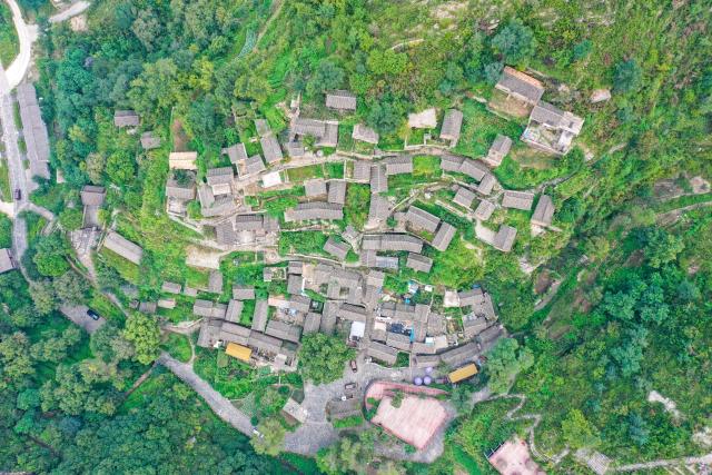 (260823) -- YANGQUAN, Aug. 23, 2026 (Xinhua) -- An aerial drone photo taken on Aug. 21, 2026 shows a view of Dapin Village in Yuxian County, Yangquan City of north China's Shanxi Province. Dapin Village, located deep in Taihang Mountain, is a traditional village with a long history in Shanxi Province. The houses here are built mostly with a mixture of yellow clay and stone. More than 50 small courtyards are located on a protruding mountainside, layered from bottom to top, which presents a unique scenery. (Xinhua/Cao Yang)