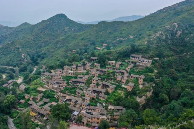 (260823) -- YANGQUAN, Aug. 23, 2026 (Xinhua) -- An aerial drone photo taken on Aug. 21, 2026 shows a view of Dapin Village in Yuxian County, Yangquan City of north China's Shanxi Province. Dapin Village, located deep in Taihang Mountain, is a traditional village with a long history in Shanxi Province. The houses here are built mostly with a mixture of yellow clay and stone. More than 50 small courtyards are located on a protruding mountainside, layered from bottom to top, which presents a unique scenery. (Xinhua/Cao Yang)