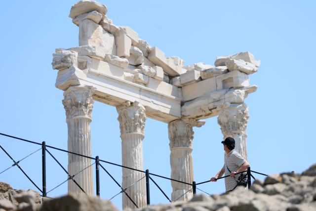 (260823) -- IZMIR, Aug. 23, 2026 (Xinhua) -- A tourist visits the Bergama ancient city in Bakircay Basin in Izmir, Türkiye, on Aug. 22, 2026. Known as Pergamon in antiquity and designated a UNESCO World Heritage site, Bergama occupies a strategic position overlooking fertile lands and vital water resources. At its heart lies the Bergama Acropolis, a landmark distinguished by its multilayered history spanning the Hellenistic, Roman, Byzantine, Beylik, and Ottoman periods. (Mustafa Kaya/Handout via Xinhua)