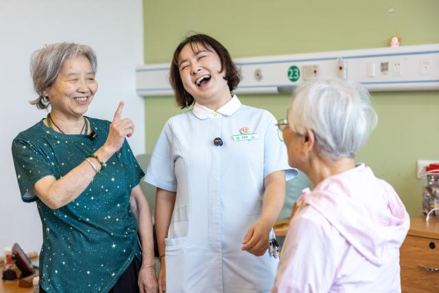 (260823) -- HUZHOU, Aug. 23, 2026 (Xinhua) -- Shen Wanting (C) laughs during a video shoot at the Shushan Healthcare Center in Huzhou City, east China's Zhejiang Province, Aug. 11, 2026.
  Senior residents at the Shushan Healthcare Center, an elderly care center in Huzhou, Zhejiang Province, sometimes misunderstand one another during daily conversations because of their advanced age. These moments inspired Shen Wanting, a post-95 nurse, and five colleagues of similar age to create micro dramas featuring these elderly residents and their daily lives at the center. 
  Five senior residents, whose average age is over 80, are regular cast members, and the oldest is over 90. 
  After gaining attention online, the production team has continued to release micro drama episodes. Since June 2025, they have produced over 160 episodes. (Photo by Yi Fan/Xinhua)