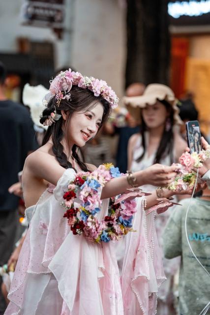 (260823) -- DALI, Aug. 23, 2026 (Xinhua) -- A woman shoots a video of herself at the ancient town of Dali in Dali, southwest China's Yunnan Province, Aug. 22, 2026. The ancient town of Dali has entered its peak tourism season during the summer holiday. According to the ancient town protection and management department, the ancient town recorded over 22 million tourist trips in the first seven months of 2026. (Xinhua/Hu Chao)