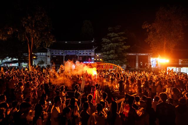 (260823) -- DALI, Aug. 23, 2026 (Xinhua) -- Tourists and local residents dance around a bonfire at the ancient town of Dali in Dali, southwest China's Yunnan Province, Aug. 20, 2026. The ancient town of Dali has entered its peak tourism season during the summer holiday. According to the ancient town protection and management department, the ancient town recorded over 22 million tourist trips in the first seven months of 2026. (Xinhua/Hu Chao)