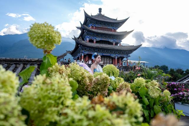 (260823) -- DALI, Aug. 23, 2026 (Xinhua) -- A tourist poses for photos at the ancient town of Dali in Dali, southwest China's Yunnan Province, Aug. 22, 2026. The ancient town of Dali has entered its peak tourism season during the summer holiday. According to the ancient town protection and management department, the ancient town recorded over 22 million tourist trips in the first seven months of 2026. (Xinhua/Hu Chao)