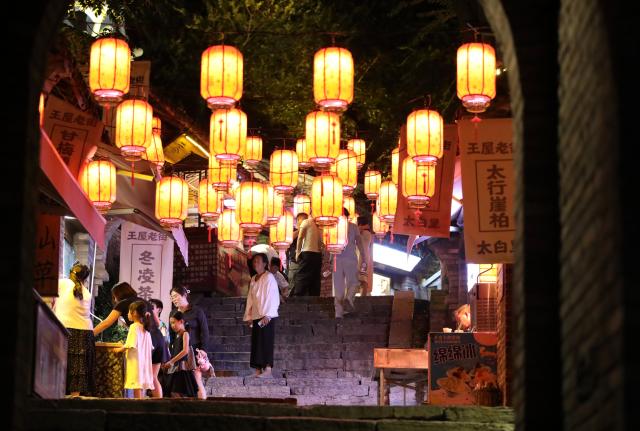 (260823) -- JIYUAN, Aug. 23, 2026 (Xinhua) -- Tourists visit a night market in the Wangwu ancient street in Yugong Village of Jiyuan, central China's Henan Province, Aug. 21, 2026. The Wangwu Mountain scenic spot witnesses a tourism boom during the summer vacation. (Photo by Duan Erping/Xinhua)