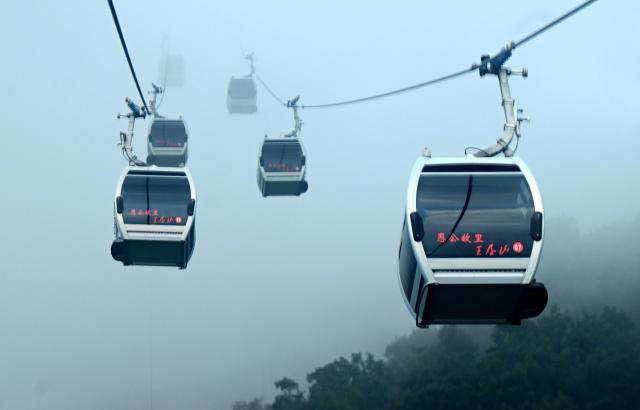 (260823) -- JIYUAN, Aug. 23, 2026 (Xinhua) -- Tourists take cable cars at the Wangwu Mountain scenic spot in Jiyuan, central China's Henan Province, Aug. 22, 2026. The Wangwu Mountain scenic spot witnesses a tourism boom during the summer vacation. (Xinhua/Zhu Xiang)