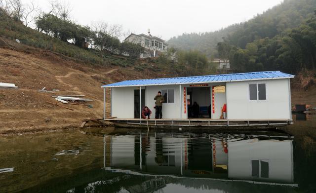 (260823) -- JINZHAI, Aug. 23, 2026 (Xinhua) -- This photo taken on Feb. 16, 2014 shows the "Haidao Clinic" built on a boat in Qishan Village of Mabu Town, Jinzhai County of Lu'an City, east China's Anhui Province. Haidao Village of Qishan Village is located deep in the mountains near the Xianghongdian Reservoir area in Jinzhai County of Lu'an City, east China's Anhui Province. Yu Jiajun, the only village doctor, takes charge of health care for more than 500 villagers there and in the surrounding areas.
   In the past, there was no clinic. Villagers had to row a boat for two or three hours to go to the health center in the Mabu Town to see the doctor. 
   After graduating from a medical school, following his father's last wishes, Yu Jiajun gave up his job in the city and returned to the village where he was born to work as a village doctor in the year of 2000. In order to visit his patients timely, Yu and his wife set up their home on a wooden boat, named "Haidao Clinic," and provided medical care to villagers on the boat.
   In recent years, many changes have taken place. The clinic was rebuilt in 2019. With the help of the local government, a standardized diagnosis and treatment building was set up on the shore. Yu's work focus has also shifted from emergency treatment in the past to offering medical service for chronic diseases. 
   However, Yu still need to drive his boat to make visits, as he has been always doing in the past years. Since working as the village doctor, he has changed four boats, conducting more than 20,000 medical consultations at patients' home. 
   Yu joined the Communist Party of China (CPC) in 2014. As a village doctor, he has been fulfilling his own promise to his father and taking the responsibility as a member of the Communist Party. 
   "As long as people need me, I will keep working here," Yu said. (Photo by Chen Li/Xinhua)