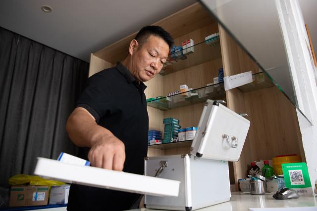 (260823) -- JINZHAI, Aug. 23, 2026 (Xinhua) -- Doctor Yu Jiajun packs up the medicines and medical devices before paying home visits at the clinic in Qishan Village of Mabu Town, Jinzhai County of Lu'an City, east China's Anhui Province, Aug. 16, 2026. Haidao Village of Qishan Village is located deep in the mountains near the Xianghongdian Reservoir area in Jinzhai County of Lu'an City, east China's Anhui Province. Yu Jiajun, the only village doctor, takes charge of health care for more than 500 villagers there and in the surrounding areas.
   In the past, there was no clinic. Villagers had to row a boat for two or three hours to go to the health center in the Mabu Town to see the doctor. 
   After graduating from a medical school, following his father's last wishes, Yu Jiajun gave up his job in the city and returned to the village where he was born to work as a village doctor in the year of 2000. In order to visit his patients timely, Yu and his wife set up their home on a wooden boat, named "Haidao Clinic," and provided medical care to villagers on the boat.
   In recent years, many changes have taken place. The clinic was rebuilt in 2019. With the help of the local government, a standardized diagnosis and treatment building was set up on the shore. Yu's work focus has also shifted from emergency treatment in the past to offering medical service for chronic diseases. 
   However, Yu still need to drive his boat to make visits, as he has been always doing in the past years. Since working as the village doctor, he has changed four boats, conducting more than 20,000 medical consultations at patients' home. 
   Yu joined the Communist Party of China (CPC) in 2014. As a village doctor, he has been fulfilling his own promise to his father and taking the responsibility as a member of the Communist Party. 
   "As long as people need me, I will keep working here," Yu said. (Xinhua/Zhang Duan)