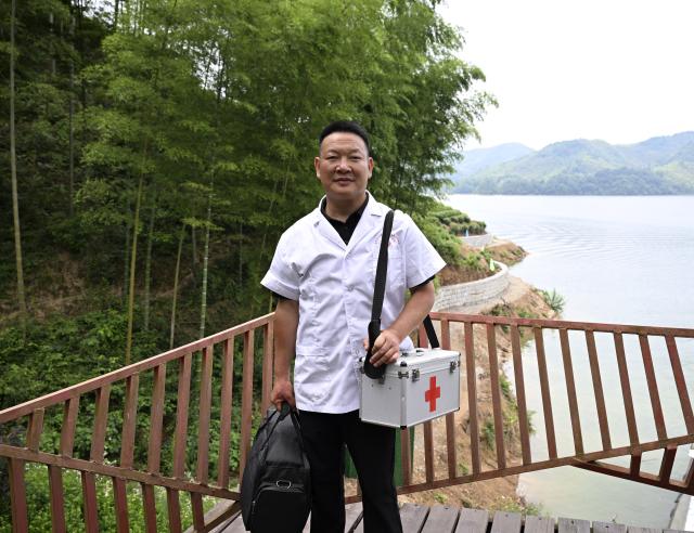 (260823) -- JINZHAI, Aug. 23, 2026 (Xinhua) -- Doctor Yu Jiajun takes a photo after paying a home visit to villagers at the clinic in Qishan Village of Mabu Town, Jinzhai County of Lu'an City, east China's Anhui Province, June 26, 2026. Haidao Village of Qishan Village is located deep in the mountains near the Xianghongdian Reservoir area in Jinzhai County of Lu'an City, east China's Anhui Province. Yu Jiajun, the only village doctor, takes charge of health care for more than 500 villagers there and in the surrounding areas.
   In the past, there was no clinic. Villagers had to row a boat for two or three hours to go to the health center in the Mabu Town to see the doctor. 
   After graduating from a medical school, following his father's last wishes, Yu Jiajun gave up his job in the city and returned to the village where he was born to work as a village doctor in the year of 2000. In order to visit his patients timely, Yu and his wife set up their home on a wooden boat, named "Haidao Clinic," and provided medical care to villagers on the boat.
   In recent years, many changes have taken place. The clinic was rebuilt in 2019. With the help of the local government, a standardized diagnosis and treatment building was set up on the shore. Yu's work focus has also shifted from emergency treatment in the past to offering medical service for chronic diseases. 
   However, Yu still need to drive his boat to make visits, as he has been always doing in the past years. Since working as the village doctor, he has changed four boats, conducting more than 20,000 medical consultations at patients' home. 
   Yu joined the Communist Party of China (CPC) in 2014. As a village doctor, he has been fulfilling his own promise to his father and taking the responsibility as a member of the Communist Party. 
   "As long as people need me, I will keep working here," Yu said. (Xinhua/Huang Bohan)