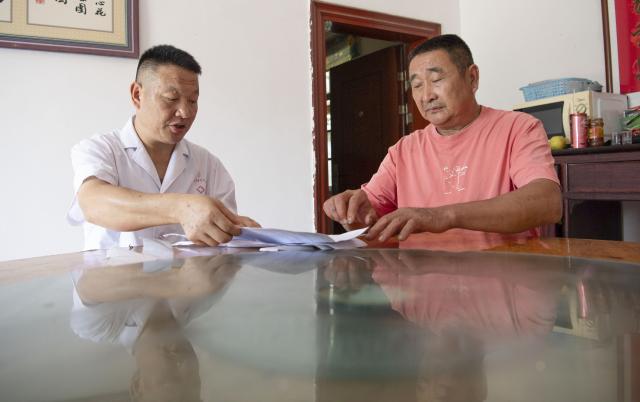 (260823) -- JINZHAI, Aug. 23, 2026 (Xinhua) -- Doctor Yu Jiajun (L) pays a home visit at the home of villager Zhang Chudong in Qishan Village of Mabu Town, Jinzhai County of Lu'an City, east China's Anhui Province, Aug. 4, 2026. Haidao Village of Qishan Village is located deep in the mountains near the Xianghongdian Reservoir area in Jinzhai County of Lu'an City, east China's Anhui Province. Yu Jiajun, the only village doctor, takes charge of health care for more than 500 villagers there and in the surrounding areas.
   In the past, there was no clinic. Villagers had to row a boat for two or three hours to go to the health center in the Mabu Town to see the doctor. 
   After graduating from a medical school, following his father's last wishes, Yu Jiajun gave up his job in the city and returned to the village where he was born to work as a village doctor in the year of 2000. In order to visit his patients timely, Yu and his wife set up their home on a wooden boat, named "Haidao Clinic," and provided medical care to villagers on the boat.
   In recent years, many changes have taken place. The clinic was rebuilt in 2019. With the help of the local government, a standardized diagnosis and treatment building was set up on the shore. Yu's work focus has also shifted from emergency treatment in the past to offering medical service for chronic diseases. 
   However, Yu still need to drive his boat to make visits, as he has been always doing in the past years. Since working as the village doctor, he has changed four boats, conducting more than 20,000 medical consultations at patients' home. 
   Yu joined the Communist Party of China (CPC) in 2014. As a village doctor, he has been fulfilling his own promise to his father and taking the responsibility as a member of the Communist Party. 
   "As long as people need me, I will keep working here," Yu said. (Xinhua/Zhang Duan)