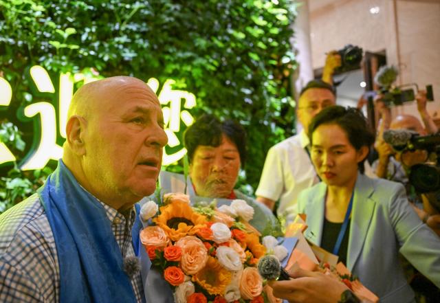 (260823) -- ORDOS, Aug. 23, 2026 (Xinhua) -- Yin Yuzhen is reunited with Ronald Sakolsky at an airport in Ordos, north China's Inner Mongolia Autonomous Region, Aug. 23, 2026.
  Retired U.S. teacher Ronald Sakolsky, who once supported China's desertification control efforts, arrived in Ordos on Sunday and was reunited with his friend Yin Yuzhen, a national model worker who has been planting trees in the Maowusu Sandy Land for four decades.
  Their story began in 1999, when Sakolsky taught English at a school in central China's Henan Province under a teachers' exchange program between the two countries.
  After watching a television news report featuring Yin's tireless work, he was deeply moved and raised 5,000 U.S. dollars to help Yin and her husband in their afforestation efforts against desertification.
  The saplings bought and planted with that donation have since grown into a forest of more than 50,000 towering trees. (Xinhua/Lian Zhen)