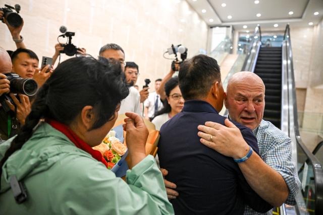 (260823) -- ORDOS, Aug. 23, 2026 (Xinhua) -- Ronald Sakolsky hugs Yin Yuzhen's husband Bai Wanxiang at an airport in Ordos, north China's Inner Mongolia Autonomous Region, Aug. 23, 2026.
  Retired U.S. teacher Ronald Sakolsky, who once supported China's desertification control efforts, arrived in Ordos on Sunday and was reunited with his friend Yin Yuzhen, a national model worker who has been planting trees in the Maowusu Sandy Land for four decades.
  Their story began in 1999, when Sakolsky taught English at a school in central China's Henan Province under a teachers' exchange program between the two countries.
  After watching a television news report featuring Yin's tireless work, he was deeply moved and raised 5,000 U.S. dollars to help Yin and her husband in their afforestation efforts against desertification.
  The saplings bought and planted with that donation have since grown into a forest of more than 50,000 towering trees. (Xinhua/Lian Zhen)