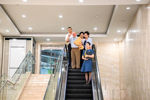 (260823) -- ORDOS, Aug. 23, 2026 (Xinhua) -- Ronald Sakolsky waves to Yin Yuzhen at an airport in Ordos, north China's Inner Mongolia Autonomous Region, Aug. 23, 2026.
  Retired U.S. teacher Ronald Sakolsky, who once supported China's desertification control efforts, arrived in Ordos on Sunday and was reunited with his friend Yin Yuzhen, a national model worker who has been planting trees in the Maowusu Sandy Land for four decades.
  Their story began in 1999, when Sakolsky taught English at a school in central China's Henan Province under a teachers' exchange program between the two countries.
  After watching a television news report featuring Yin's tireless work, he was deeply moved and raised 5,000 U.S. dollars to help Yin and her husband in their afforestation efforts against desertification.
  The saplings bought and planted with that donation have since grown into a forest of more than 50,000 towering trees. (Xinhua/Lian Zhen)