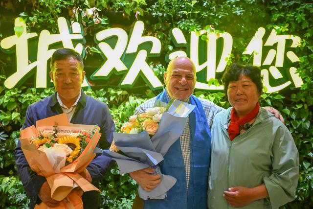 (260823) -- ORDOS, Aug. 23, 2026 (Xinhua) -- Ronald Sakolsky (C), Yin Yuzhen (R) and Yin's husband Bai Wanxiang pose for photos at an airport in Ordos, north China's Inner Mongolia Autonomous Region, Aug. 23, 2026.
  Retired U.S. teacher Ronald Sakolsky, who once supported China's desertification control efforts, arrived in Ordos on Sunday and was reunited with his friend Yin Yuzhen, a national model worker who has been planting trees in the Maowusu Sandy Land for four decades.
  Their story began in 1999, when Sakolsky taught English at a school in central China's Henan Province under a teachers' exchange program between the two countries.
  After watching a television news report featuring Yin's tireless work, he was deeply moved and raised 5,000 U.S. dollars to help Yin and her husband in their afforestation efforts against desertification.
  The saplings bought and planted with that donation have since grown into a forest of more than 50,000 towering trees. (Xinhua/Lian Zhen)