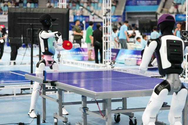 (260823) -- BEIJING, Aug. 23, 2026 (Xinhua) -- The robot of Tsinghua-Beiren TRobot Team (L) competes during a group stage match of table tennis of the 2nd World Humanoid Robot Games in Beijing, capital of China, Aug. 23, 2026. (Xinhua/Ju Huanzong)