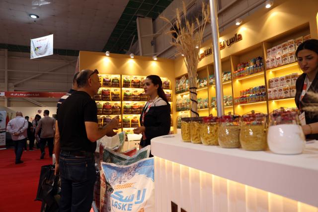 (260824) -- BAGHDAD, Aug. 24, 2026 (Xinhua) -- Two men talk with an exhibitor at the 17th Agricultural Week exhibition in Baghdad, Iraq, on Aug. 23, 2026. The 17th Agricultural Week exhibition is running from Saturday to Thursday in Iraq's capital city of Baghdad. (Xinhua/Khalil Dawood)
