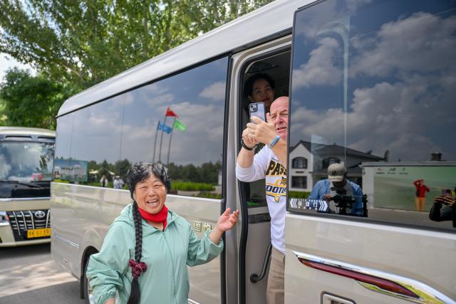 (260824) -- ORDOS, Aug. 24, 2026 (Xinhua) -- Ronald Sakolsky takes photos while arriving at Yin Yuzhen's home in Salawusu Village, Uxin Banner, north China's Inner Mongolia Autonomous Region, Aug. 24, 2026. Retired U.S. teacher Ronald Sakolsky, who once supported China's desertification control efforts, arrived in Ordos on Sunday and was reunited with his friend Yin Yuzhen, a national model worker who has been planting trees in the Maowusu Sandy Land for four decades. He then visited her home on Monday.
   Their story began in 1999, when Sakolsky taught English at a school in central China's Henan Province under a teachers' exchange program between the two countries.
   After watching a television news report featuring Yin's tireless work, he was deeply moved and raised 5,000 U.S. dollars to help Yin and her husband in their afforestation efforts against desertification.
   The saplings bought and planted with that donation have since grown into a forest of more than 50,000 towering trees. (Xinhua/Lian Zhen)