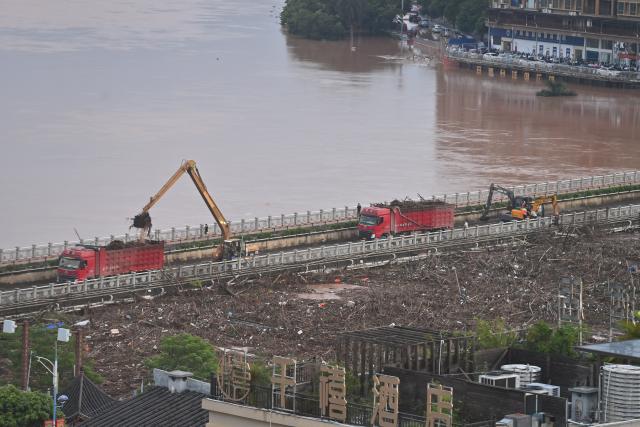 (260824) -- NINGMING, Aug. 24, 2026 (Xinhua) -- Rescue vehicles are deployed on a bridge to help remove flood debris in the Mingjiang River in Ningming County, south China's Guangxi Zhuang Autonomous Region, Aug. 24, 2026. Rescue forces have been deployed in Ningming County where typhoon-triggered heavy rainfall caused flood in the Mingjiang River and its tributaries on Sunday. (Xinhua/Zhou Hua)