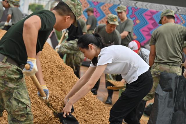 (260824) -- NINGMING, Aug. 24, 2026 (Xinhua) -- Rescuers prepare sandbags as flood control supplies along the banks of the Mingjiang River in Ningming County, south China's Guangxi Zhuang Autonomous Region, Aug. 24, 2026. Rescue forces have been deployed in Ningming County where typhoon-triggered heavy rainfall caused flood in the Mingjiang River and its tributaries on Sunday. (Xinhua/Zhou Hua)