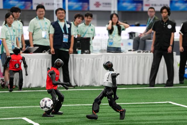 (260824) -- BEIJING, Aug. 24, 2026 (Xinhua) -- Robots (L) of CAU Mountain&Sea competes with robots of B-human during the 5v5 Medium Robot Group of Soccer match of the 2nd World Humanoid Robot Games in Beijing, capital of China, Aug. 24, 2026. (Xinhua/Ju Huanzong)