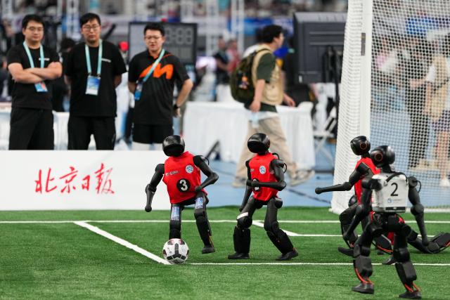 (260824) -- BEIJING, Aug. 24, 2026 (Xinhua) -- Robots (L) of CAU Mountain&Sea competes with robots of B-human during the 5v5 Medium Robot Group of Soccer match of the 2nd World Humanoid Robot Games in Beijing, capital of China, Aug. 24, 2026. (Xinhua/Ju Huanzong)