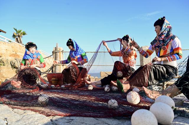 (260824) -- FUZHOU, Aug. 24, 2026 (Xinhua) -- Performers demonstrate net weaving at a scenic spot in Dazuo Village of Hui'an County, southeast China's Fujian Province, Aug. 17, 2026. Dazuo Village is surrounded by the sea on three sides. In recent years, the village has focused on cultivating the traditional customs, launching experiential activities such as net weaving and travel photography to attract tourists. (Xinhua/Lin Shanchuan)