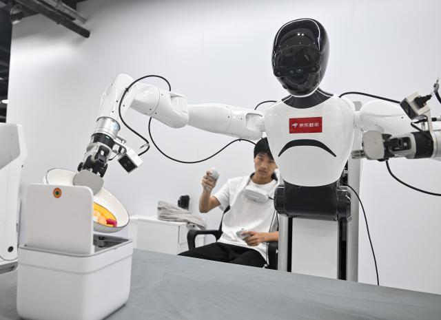 (260825) -- BEIJING, Aug. 25, 2026 (Xinhua) -- A technician trains a robot at a robot data collection center of Chinese e-commerce giant JD.com in Suqian, east China's Jiangsu Province, Aug. 24, 2026. In operation since October 2025, JD.com's robot data collection center is a provincial-level embodied intelligent robot data collection center in east China's Jiangsu Province. The facility enhances the data collection scenarios in terms of physical fidelity, generalization ability, and interaction quality. It upgrades the data collection environment to a real physical scene, transforming the data collection center from a static sample library into a training ground for embodied intelligent robots. (Xinhua/Ji Chunpeng)